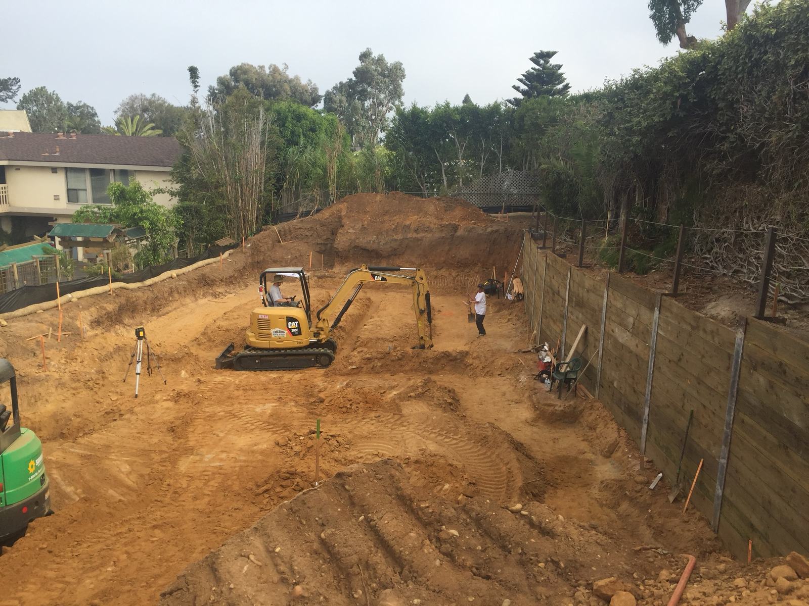 Mini excavator shaping the basement pad against the shoring