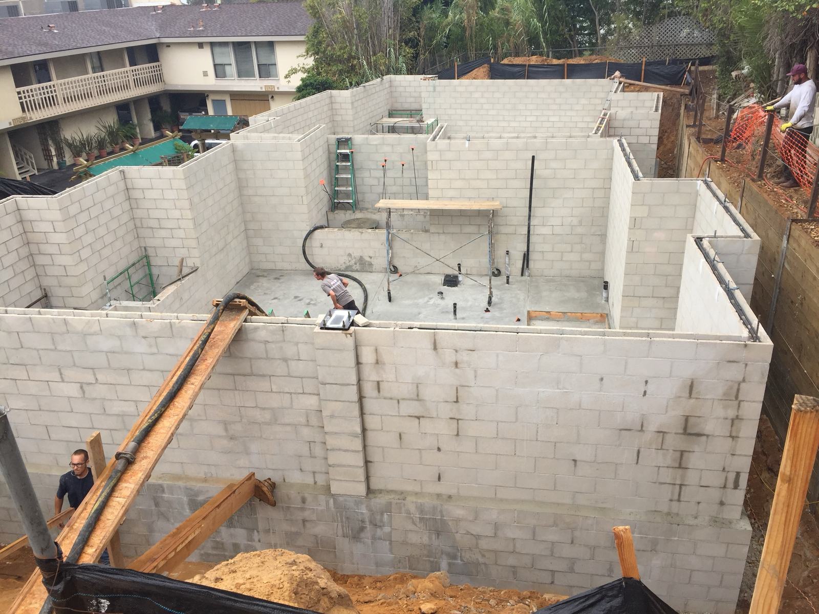 Reinforced CMU basement walls being grouted by pump